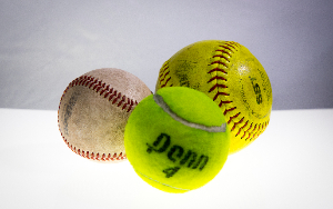 A baseball, tennis ball, and softball are pictured 